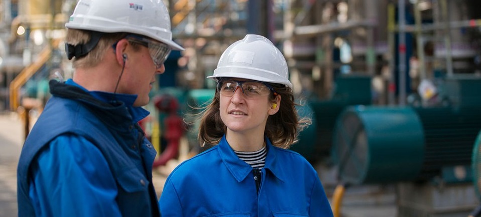 Un homme et une femme sur un chantier avec des casques blancs et des tenues bleues 